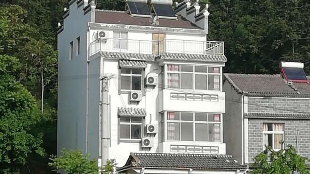 A multi-story building with traditional architectural features, including a balcony and solar panels on the roof. - Qingliangzhai Liu Yinong Family Lodging (Wuhan)