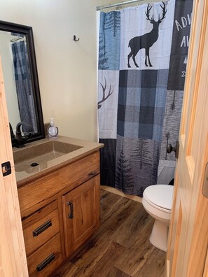 A bathroom with a wooden vanity, a mirror, a sink, and a toilet.