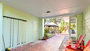 Ein überdachter Patio-Bereich mit einem Hütchenspiel, Sitzgelegenheiten im Freien und einer Laube.
