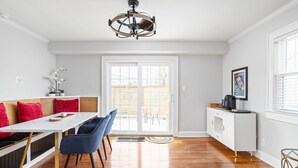Una cocina moderna con comedor, que presenta una mesa blanca, sillas azules y un armario blanco.