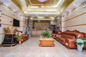 A spacious lobby with a reception desk, leather sofas, a coffee table, and decorative plants. - Haowanjia Hotel (Kunming)