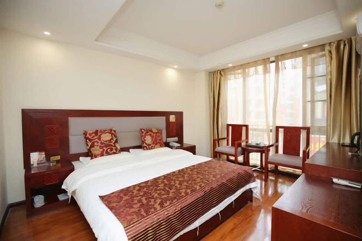 A hotel room with a large bed, wooden headboard, two bedside tables, a desk, and a chair.