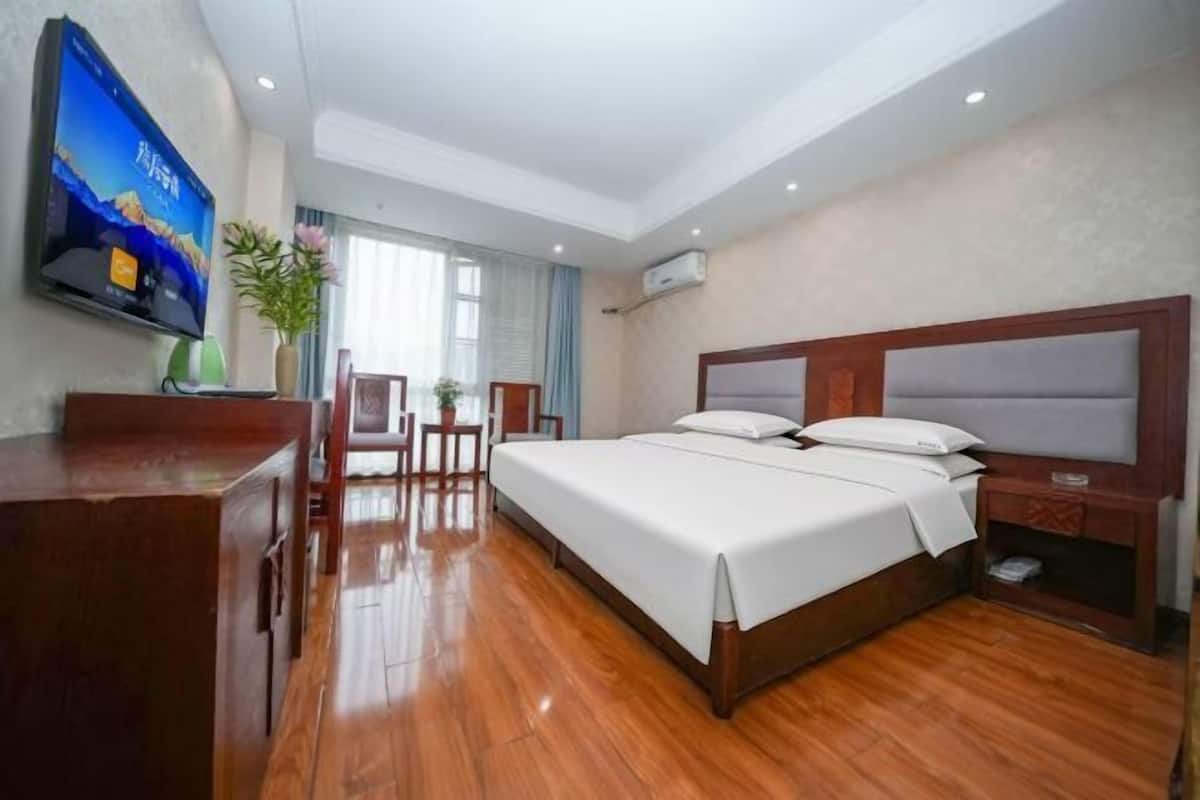 A hotel room with a bed, a desk, a TV, and a window.