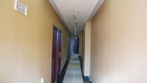 Een hotelhal met een bord aan de muur, een deur links en een lamp aan het plafond.
