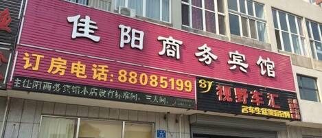 A building with a red signboard displaying the name and contact number of a hotel.