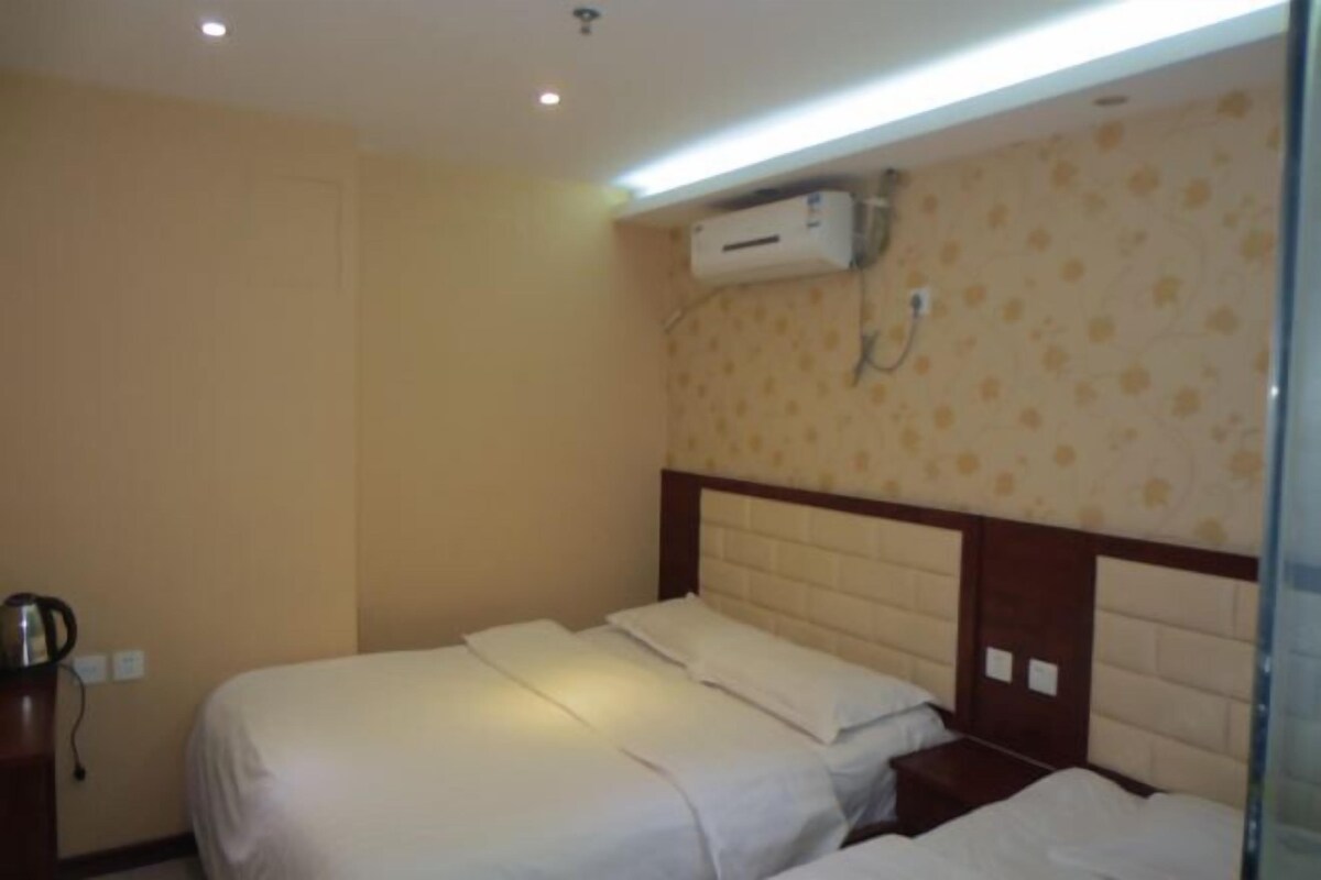 Een hotelkamer met een bed, nachtkastje, airconditioning en een wandheater.