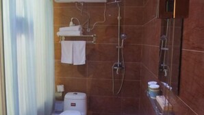 Een badkamer met een douche, toilet en handdoekhouder.