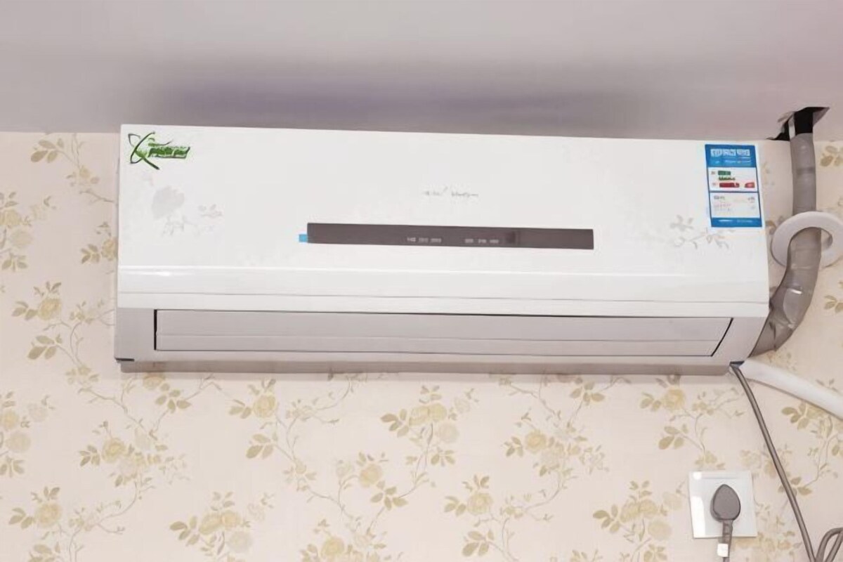 Een wandairconditioner met bedieningspaneel en een stopcontact.