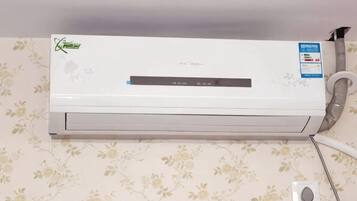A wall-mounted air conditioner with a control panel and a power outlet.