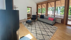A spacious living room with a large window, a sofa, a chair, and a fireplace.
