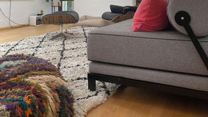 A modern living room with a sofa, a TV, and large windows.