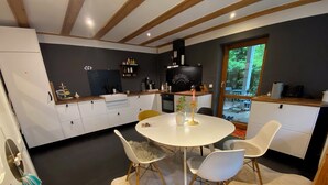 A modern kitchen with white cabinets, a round dining table, and a large window.