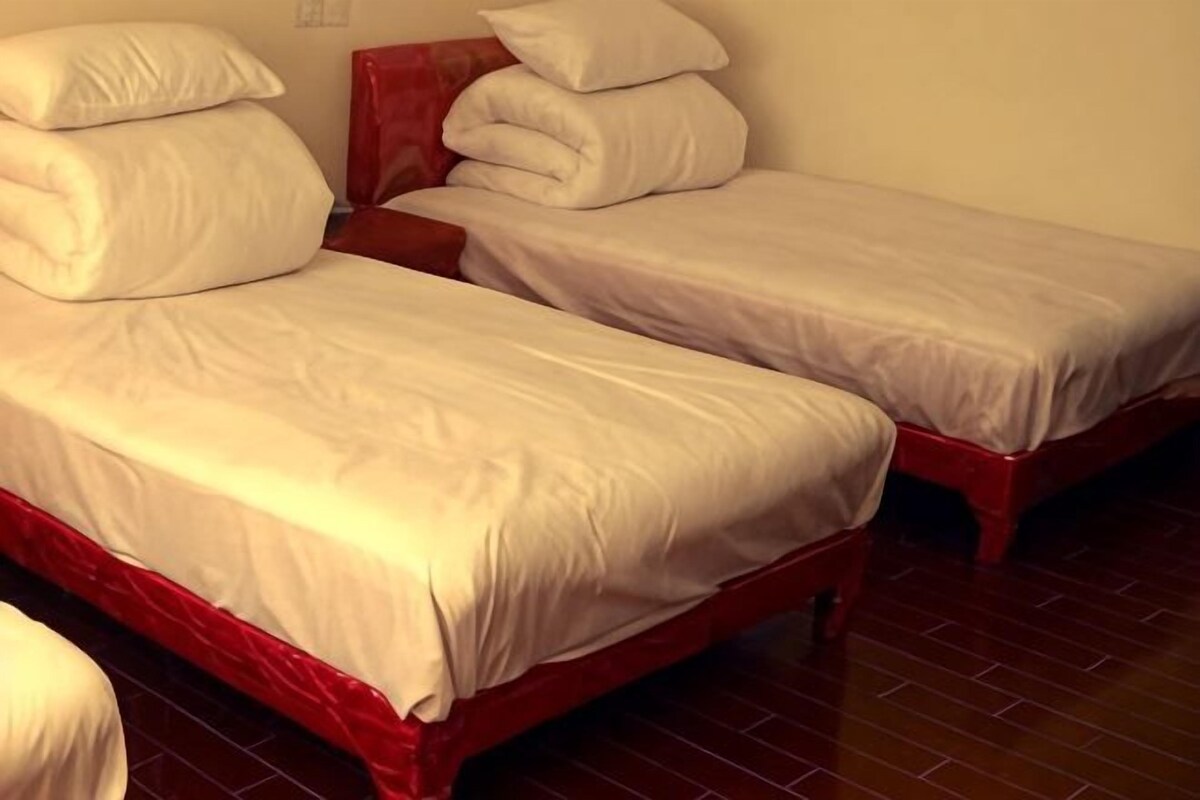 A room with two single beds, each with a red frame and white bedding.