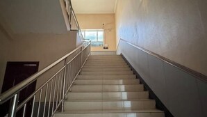A staircase with a metal railing, leading to a landing with a window. - Haosen Hotel (Urumqi)
