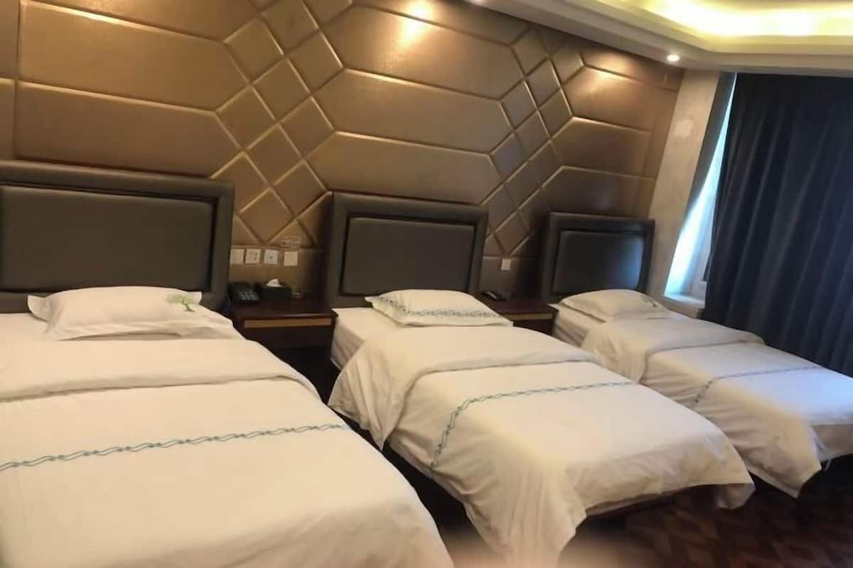 A hotel room with four single beds arranged in a row, a large wall panel with a geometric pattern, and a dark curtain on the window.
