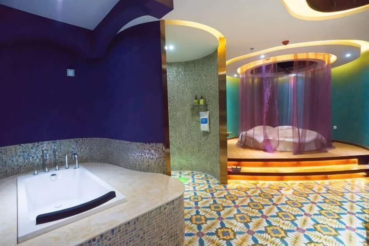 A modern bathroom with a large bathtub, a shower area with a curtain, and a patterned floor.