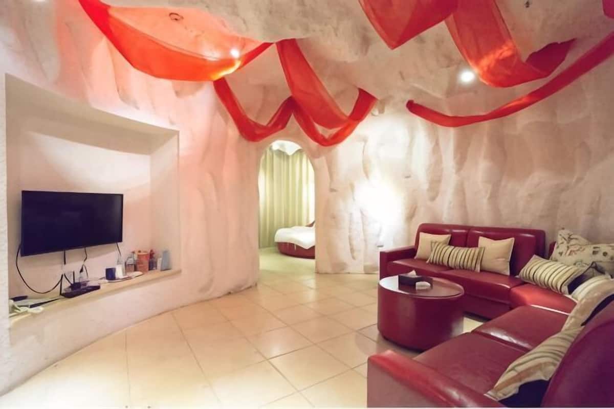 A room with a flat-screen TV, a red sofa, and a red chair.