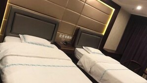 A hotel room with two beds, each with a headboard and a nightstand. - Haosen Hotel (Urumqi)