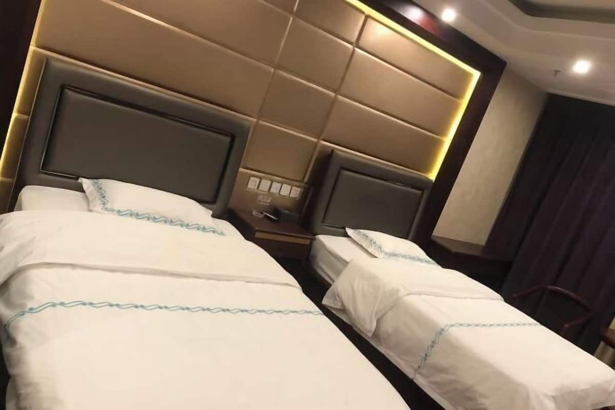 A hotel room with two beds, each with a headboard and a nightstand.