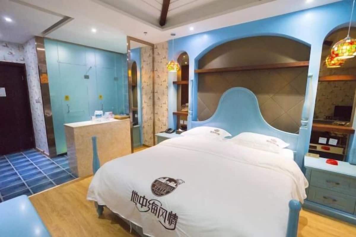 A bedroom with a bed, a bedside table, a nightstand, a desk, and a chair.