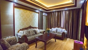 A living room with two sofas, a coffee table, and a television. - Haosen Hotel (Urumqi)