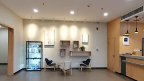 Un espace d’accueil comprenant un comptoir, deux chaises, une petite table et un présentoir.