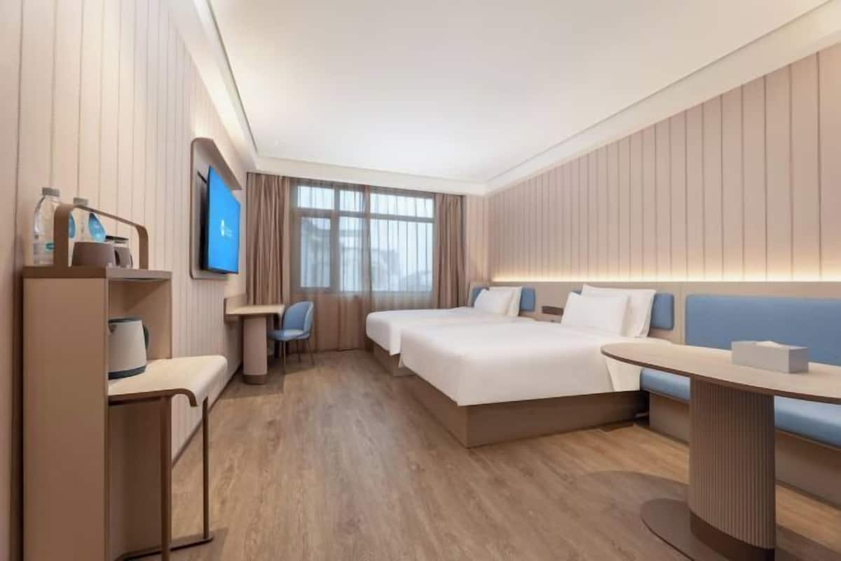 Ein modernes Hotelzimmer mit einem großen Bett, einem Schreibtisch, einem Sessel und einem Fernseher.