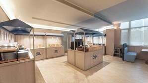 Une chambre d’hôtel moderne dotée d’une kitchenette, d’un coin salon et de grandes fenêtres.