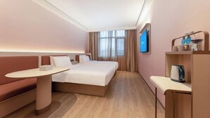 Une chambre d’hôtel moderne équipée d’un lit, d’un canapé, d’une petite table et d’un téléviseur fixé au mur.