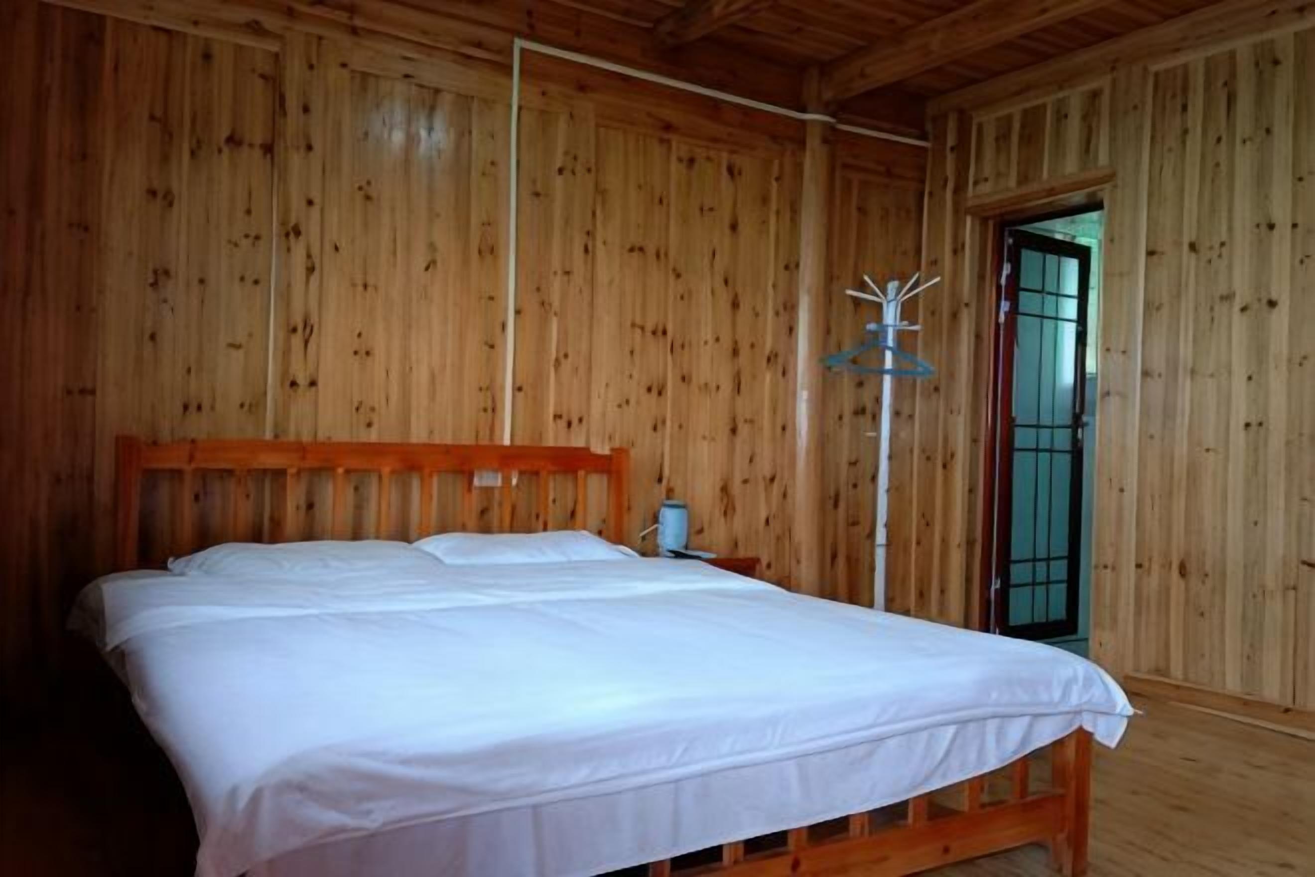 Une pièce en bois avec un lit, une table de chevet et une porte surmontée d’un portail en métal.