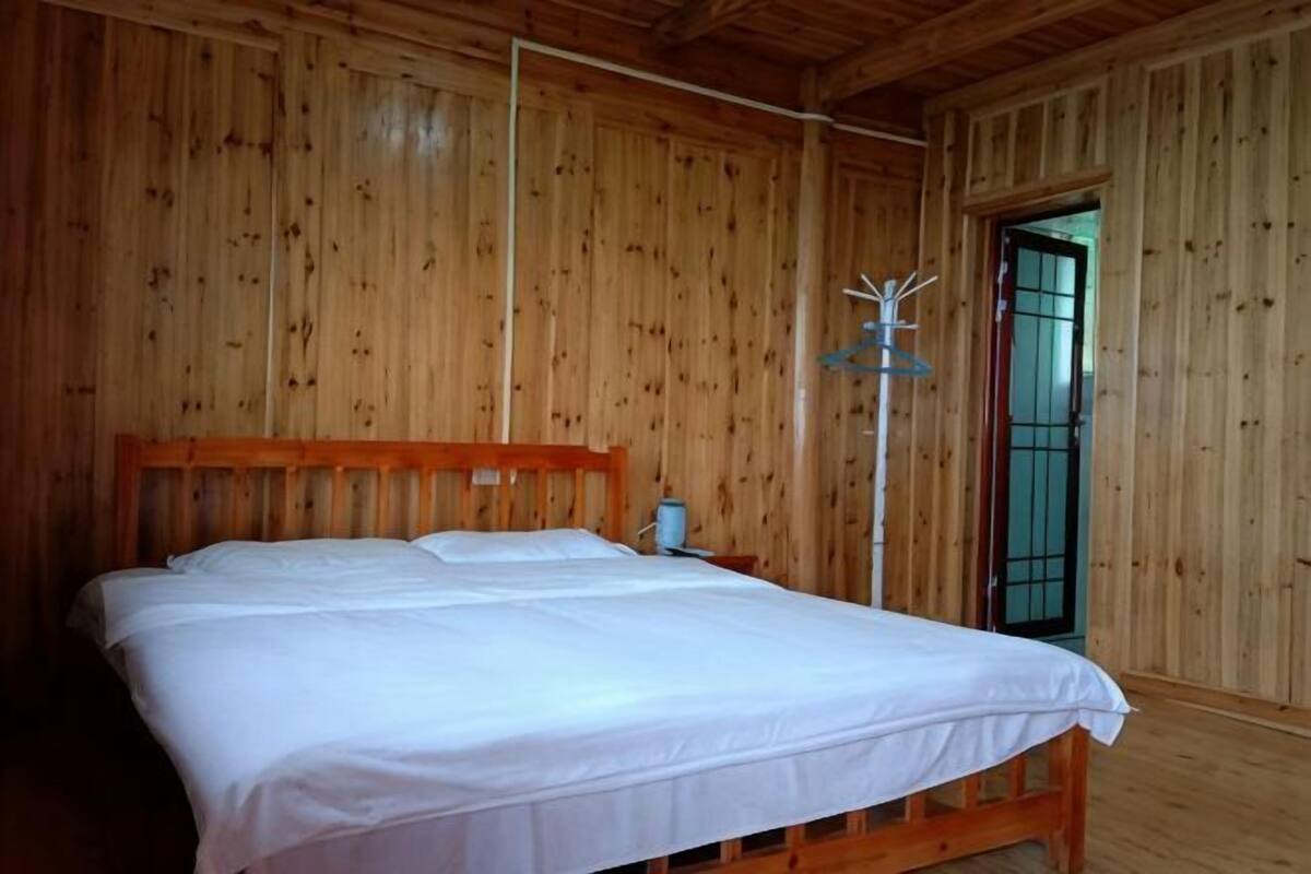 Een houten kamer met een bed, een nachtkastje en een deur met een metalen hekwerk.