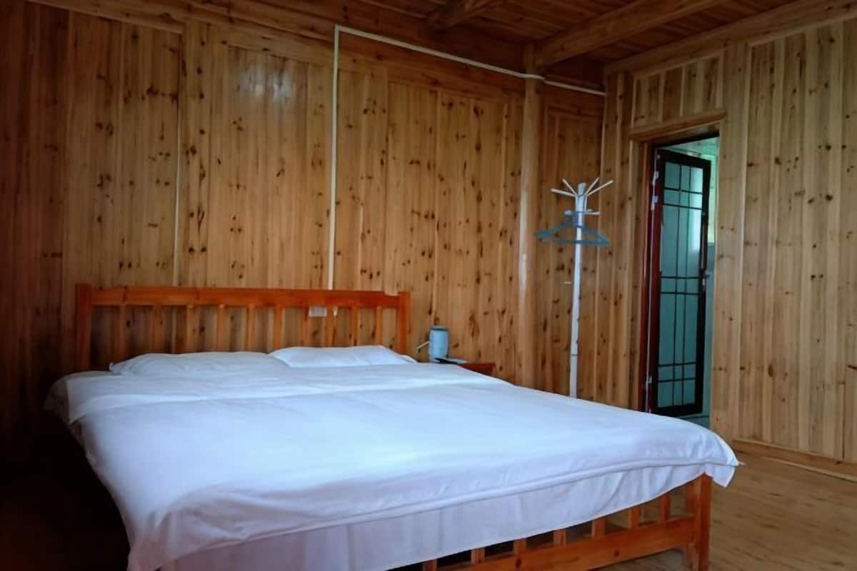 Une piĂšce en bois avec un lit, une table de chevet et une porte surmontĂ©e dâun portail en mĂ©tal.