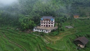 Un edificio de varios pisos rodeado de campos en terrazas, probablemente un alojamiento rural u hospedaje.