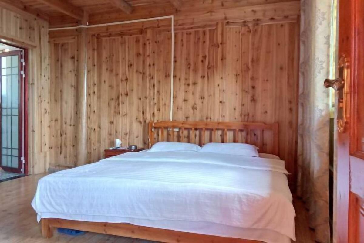 Een houten kamer met een bed, nachtkastje en een deur.