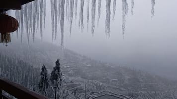 A snowy landscape with icicles hanging from the ceiling, a wooden railing, and a view of a snow-covered village.