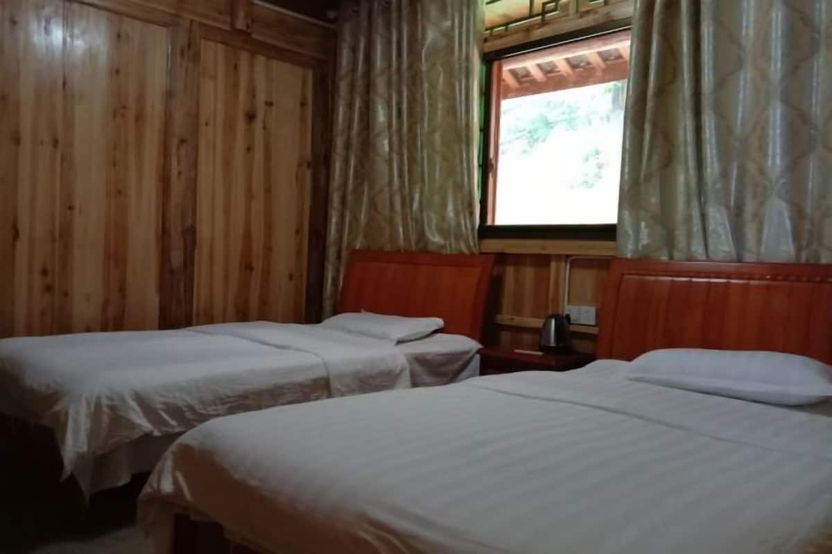 Een kamer met twee eenpersoonsbedden, houten wanden, een raam met gordijnen en een houten hoofdbord.