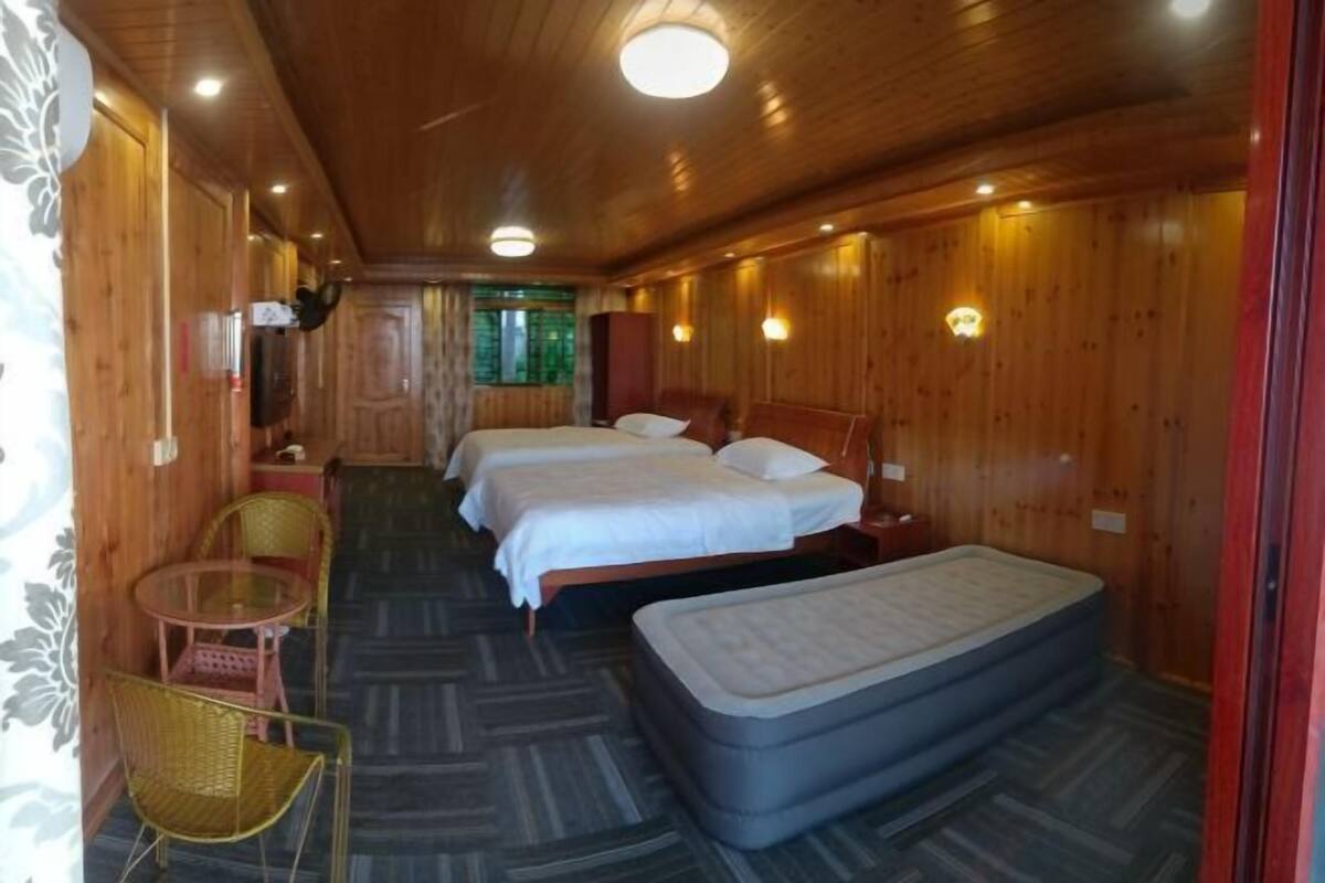 Een houten kamer met slaapkamer, twee bedden, een kleine tafel met stoelen en een matras op de vloer.