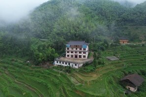 A multi-story building with a flat roof, surrounded by terraced fields, likely a rural accommodation. - Ziquejie Zhuofan Home Homestay (Xinhua)