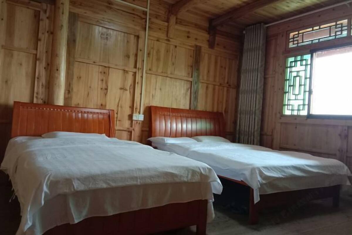 Een kamer met twee houten bedden, houten wanden en een raam met een geometrisch ontwerp.