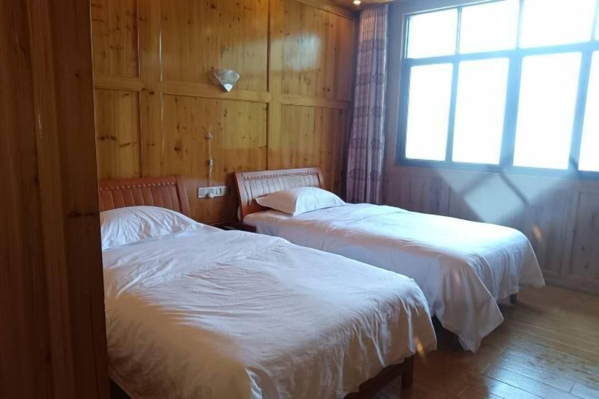 Een kamer met twee bedden, houten wanden en een groot raam.