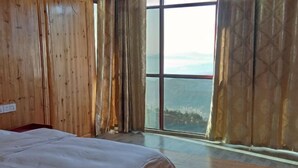 Una habitación con un ventanal grande, paredes de madera, una cama y cortinas.