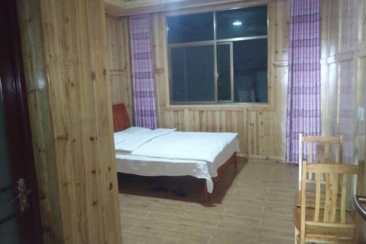 Une pièce en bois avec un lit, une fenêtre et une chaise.