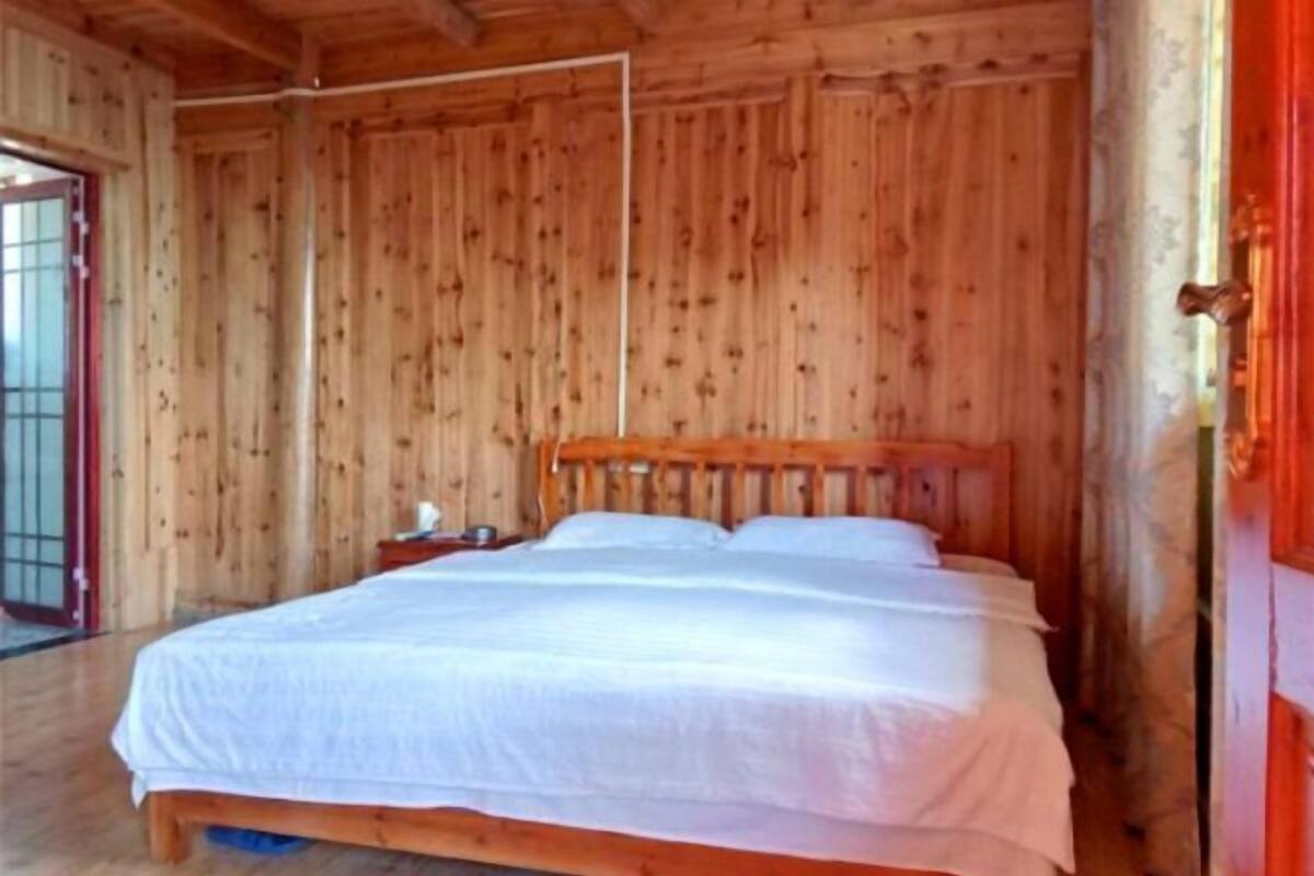Een houten kamer met een bed, een nachtkastje en een deur met een rode handgreep.