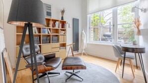 Un salon moderne avec un canapé en cuir, un pouf et une bibliothèque.