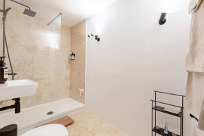 A modern bathroom with a shower, toilet, sink, and a towel rack.