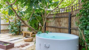 Un jardin avec un jacuzzi, une clôture en bois et un banc en bois.