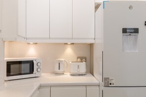 A kitchen with a microwave, toaster, and water dispenser. - Roomy 3BD by Hampstead Heath! (London)