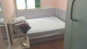A small room with a single bed, a bedside table with a vase, and a window with curtains. - Xiyuan Accommodation (Wuhan Union Hospital Zhongshan Park Branch) (Wuhan)