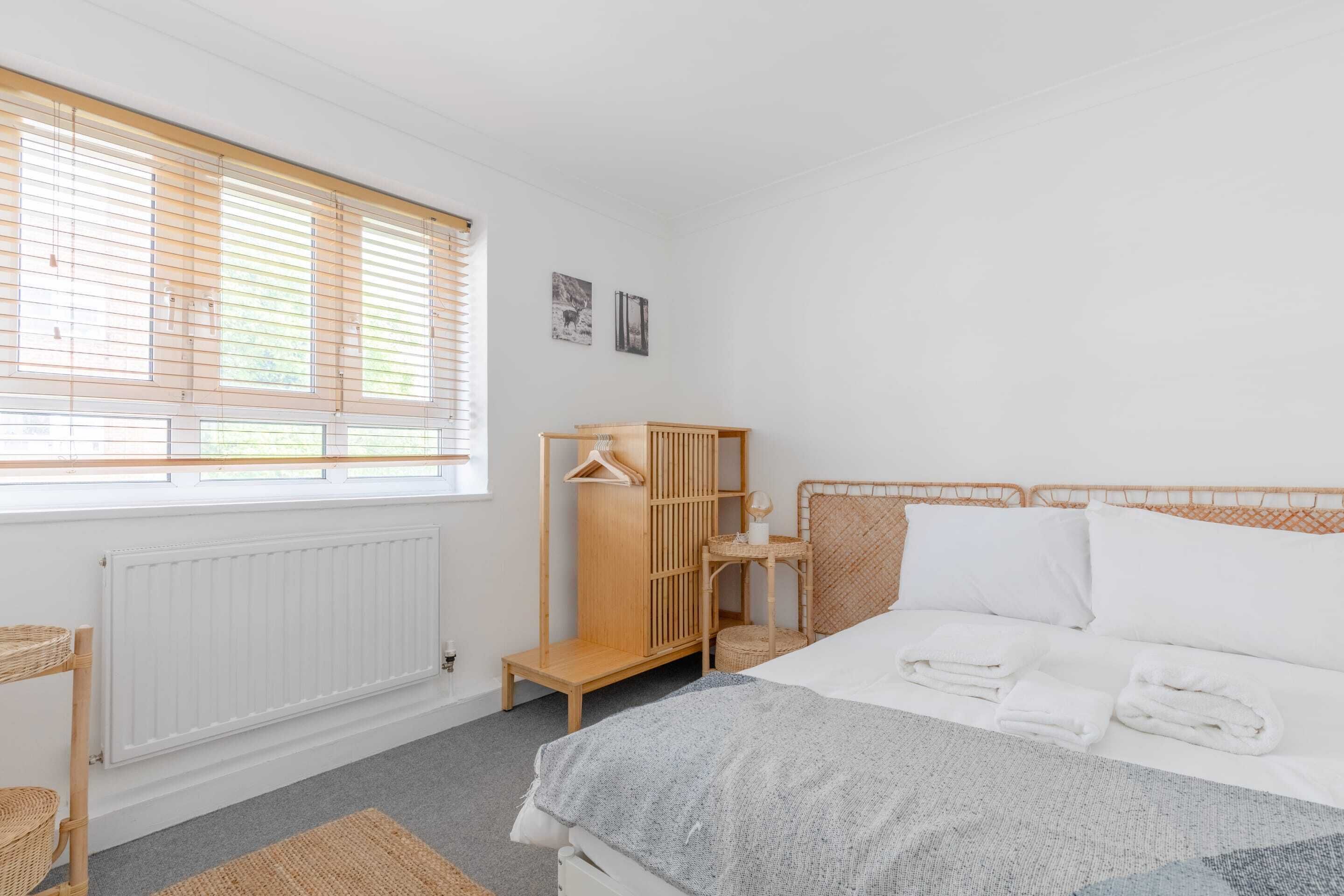 Une chambre à coucher avec un lit, une armoire en bois, un radiateur et une fenêtre avec des stores.