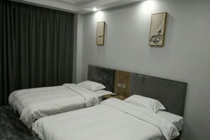 A hotel room with two single beds, a wooden headboard, a nightstand, and two wall-mounted artworks. - Nancheng Xilaike Hotel (Nancheng)